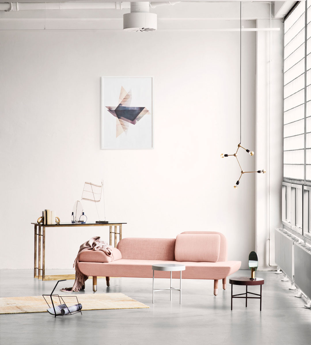 Minimalist living room with a pink sofa, small tables, modern decor, a wall art piece, and large windows letting in natural light—perfect inspiration for Trinidad Event Furniture setups or stylish Trinidad Event Rentals. - Perched Event Rentals, Trinidad