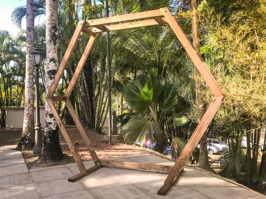 The Geometric Arch standing outdoors on a paved area, surrounded by tall trees and greenery