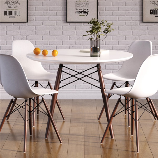 Eames Dining Table, a round white table with four white chairs, a small plant and three oranges, against a white brick wall