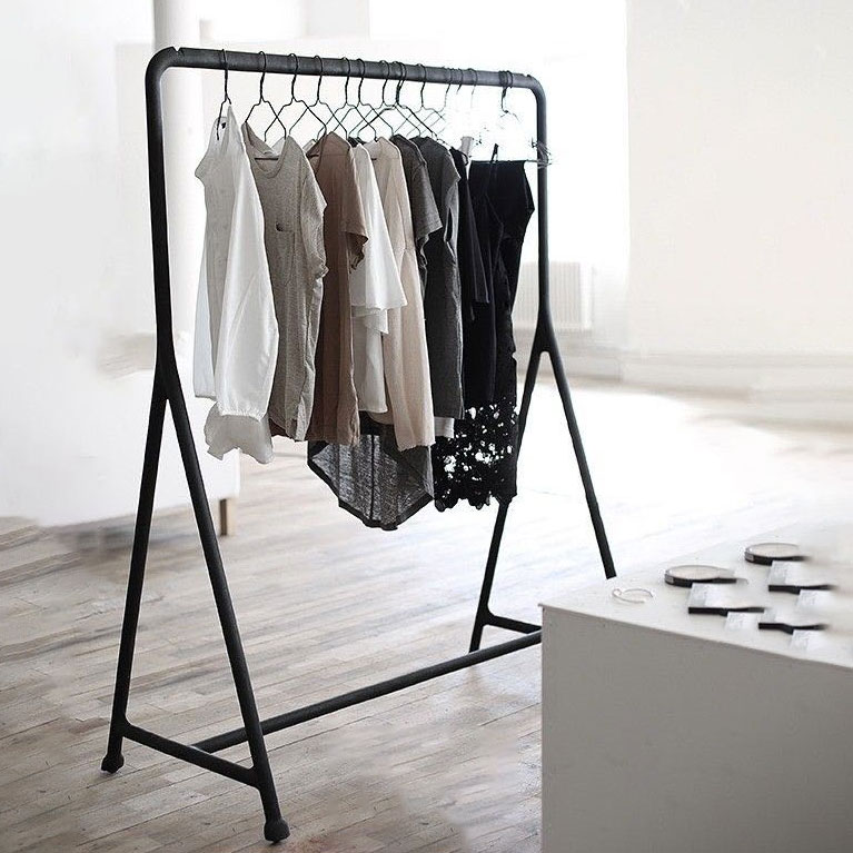 Mobile Clothing Rack holding neutral shirts and tops on hangers in a minimalist, well-lit room with wooden floors