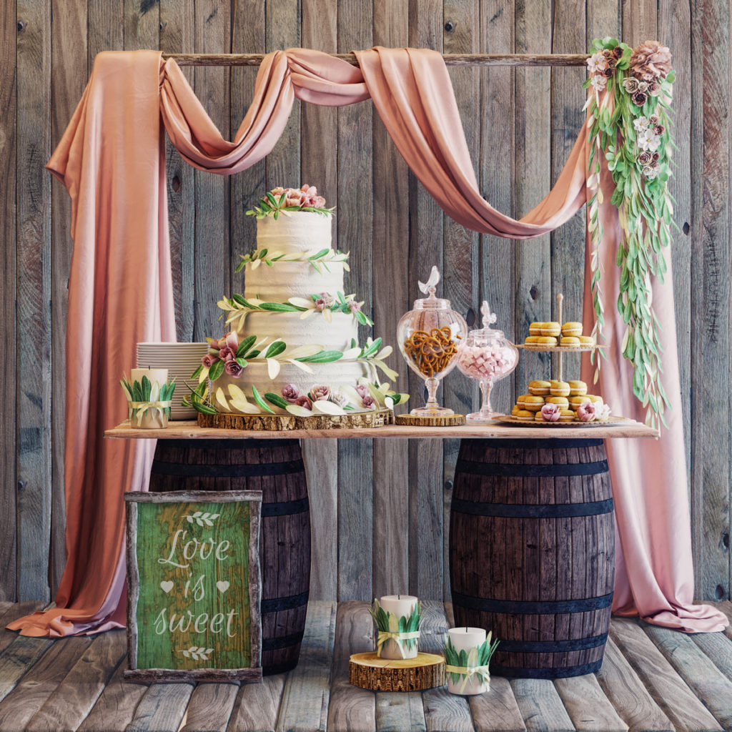 Rum Barrel Bar holding a tiered cake, sweets and macarons, with pink drapery, greenery and a Love is sweet sign