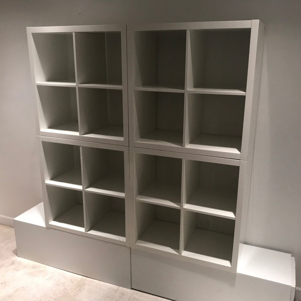 The Simple Storage Backdrop, four white cube-shaped shelving units in two columns with the right one tilted, on a white base