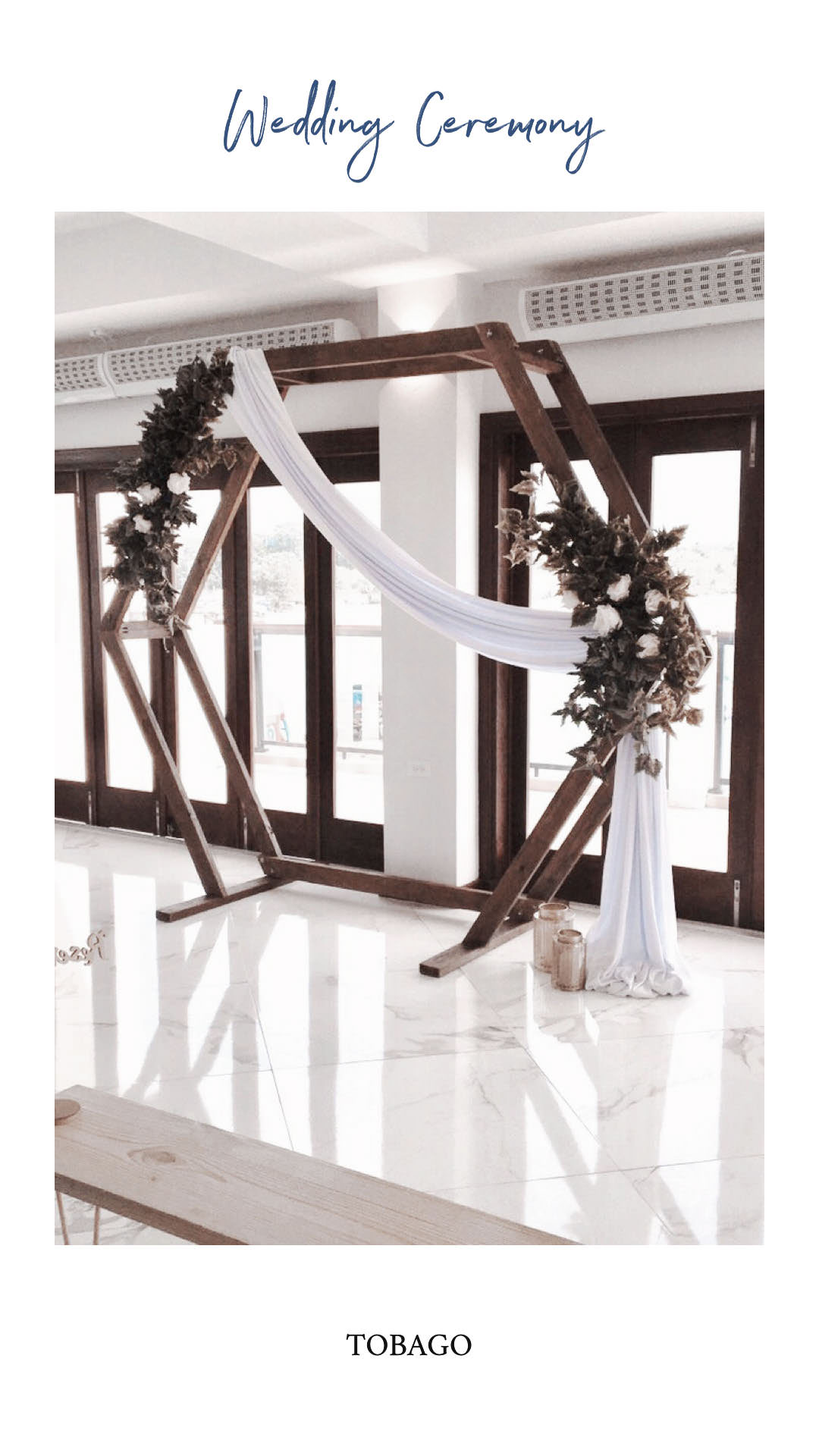 Indoor wedding ceremony with a wooden geometric arch and white drapery