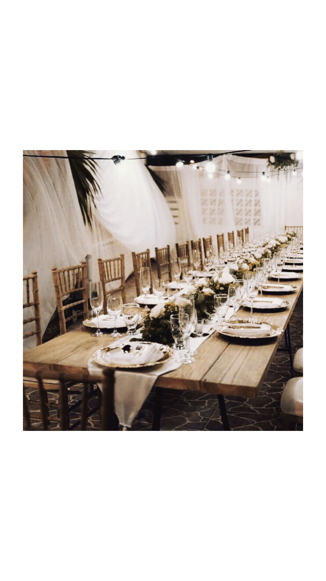 Long wooden reception table styled for an indoor wedding