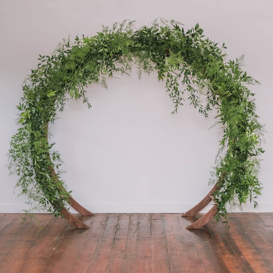 Oval Arch: A modern wooden circular arch used as a wedding ceremony arch, an entryway to the aisle or event, or a backdrop behind a pallet bar or sweetheart