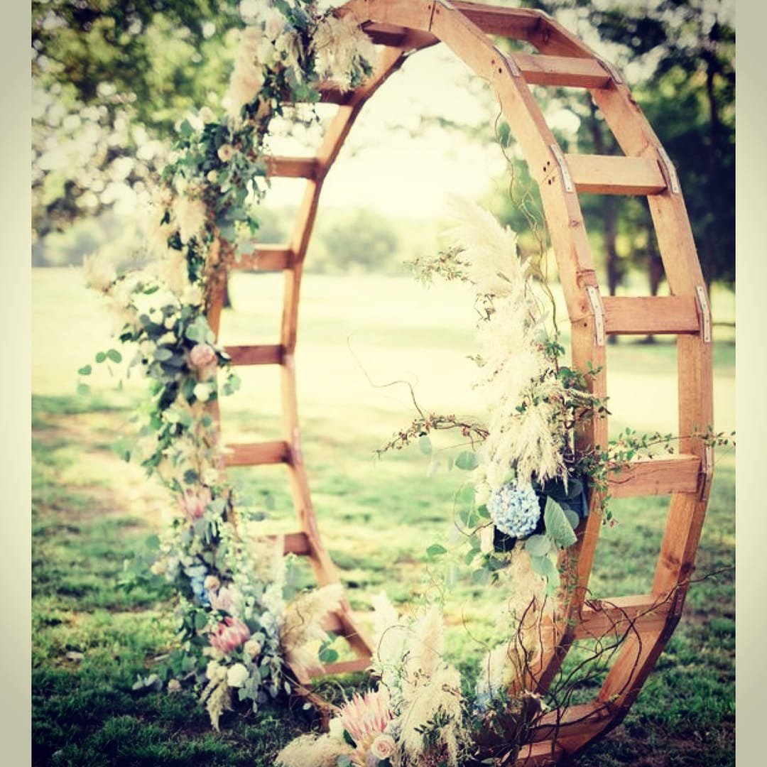 Oval Arch: A modern wooden circular arch used as a wedding ceremony arch, an entryway to the aisle or event, or a backdrop behind a pallet bar or sweetheart
