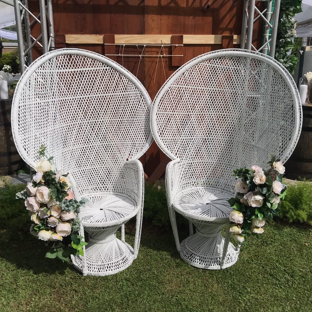Peacock Chair: A white wicker peacock chair with a high, arched back that gives it a throne-like look, available plain white or with gold trim on the backrest.